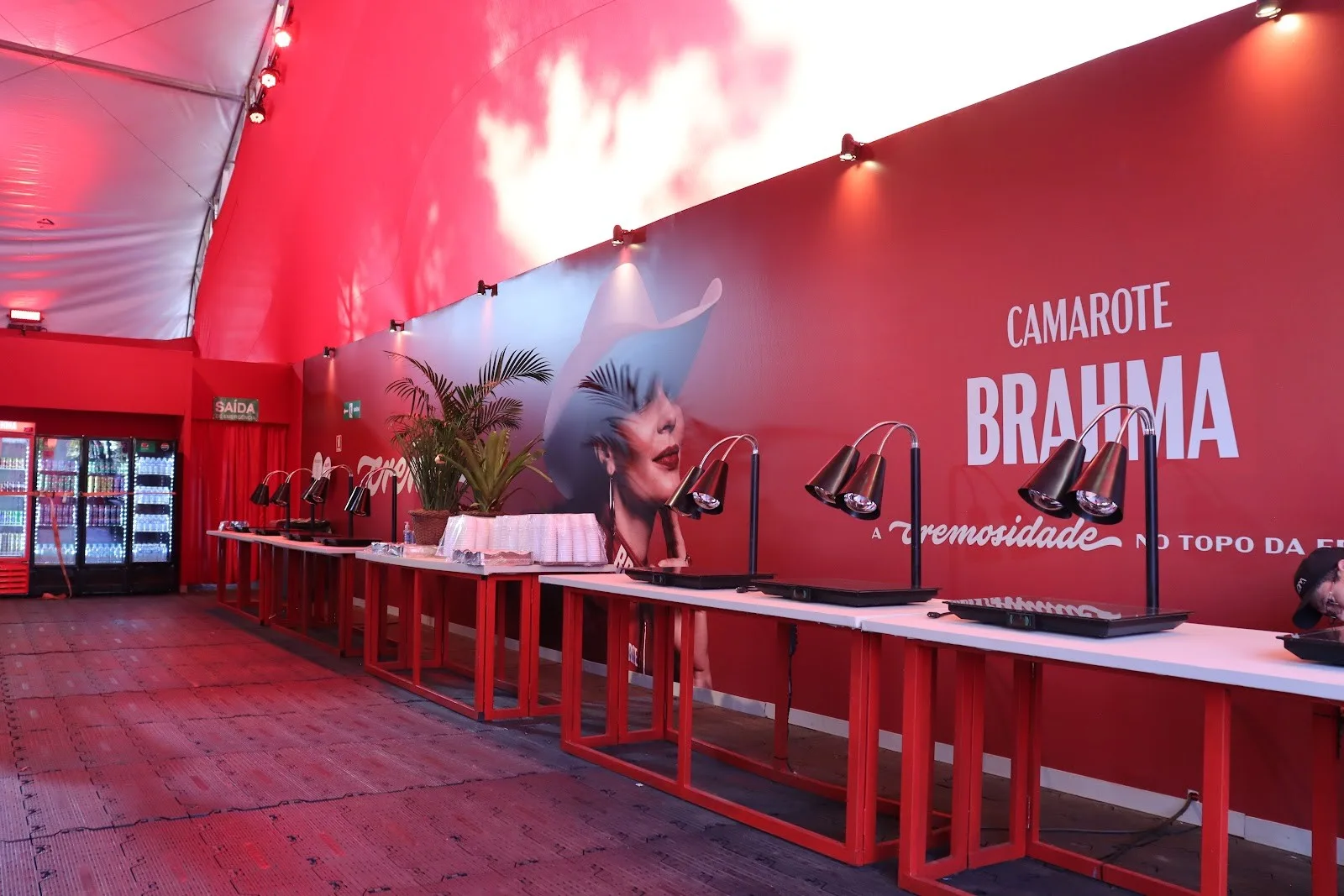 Painel vermelho do Camarote Brahma com mesas altas na Pecuária de Goiânia